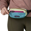 Primer plano de la riñonera Patagonia Terravia Mini Hip Pack en Patchwork: Snowmelt Blue puesta en la cintura, abierta y mostrando el diseño de bloques de color y el logo Patagonia.