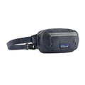 Patagonia Terravia Mini Hip Pack 1L en color smolder blue, vista de producto en tres cuartos sin modelo, mostrando el compartimento principal con franja y cremallera gris, el bolsillo frontal de seguridad con tirador azul marino, la etiqueta Patagonia con logo Fitz Roy y la correa ajustable de nailon reciclado.