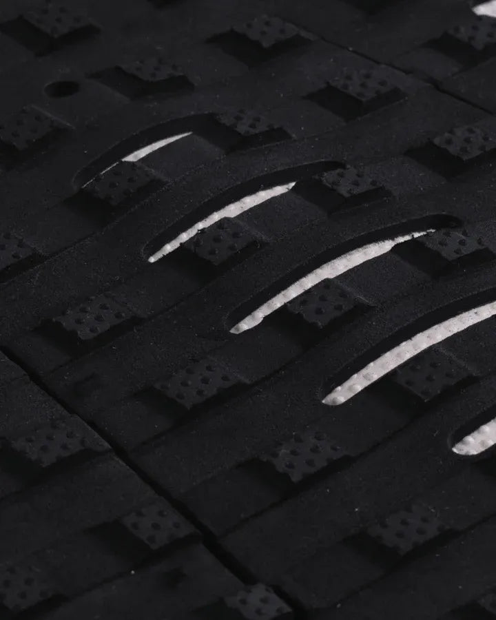 Detalle de los cortes estratégicos LOC-LITE blancos en el patrón Square Loc negro del grip de surf Creatures Mick Fanning Signature black white para máximo contacto del pie.