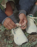 Una chica se ata las Zapatillas de trekking impermeables Vans MTE Crosspath Natural en una playa