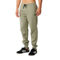 Rip Curl Anti-Series Departed Trackpant en verde surplus, vista lateral izquierda sobre modelo, con etiqueta woven negra en el muslo, bolsillo lateral y puño elástico.