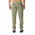 Pantalón Rip Curl Anti-Series Departed en verde surplus, vista trasera completa sobre modelo, con dos bolsillos con cremallera negra y costuras anguladas en los muslos.