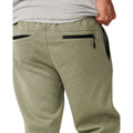 Detalle trasero del Rip Curl Anti-Series Departed Trackpant en verde surplus, con bolsillos traseros con cremallera negra y cinturilla elástica en primer plano.