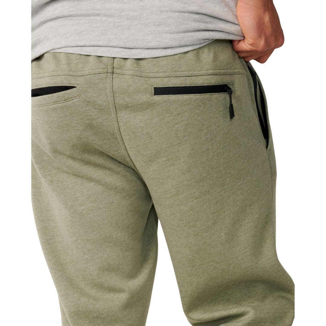Detalle trasero del Rip Curl Anti-Series Departed Trackpant en verde surplus, con bolsillos traseros con cremallera negra y cinturilla elástica en primer plano.