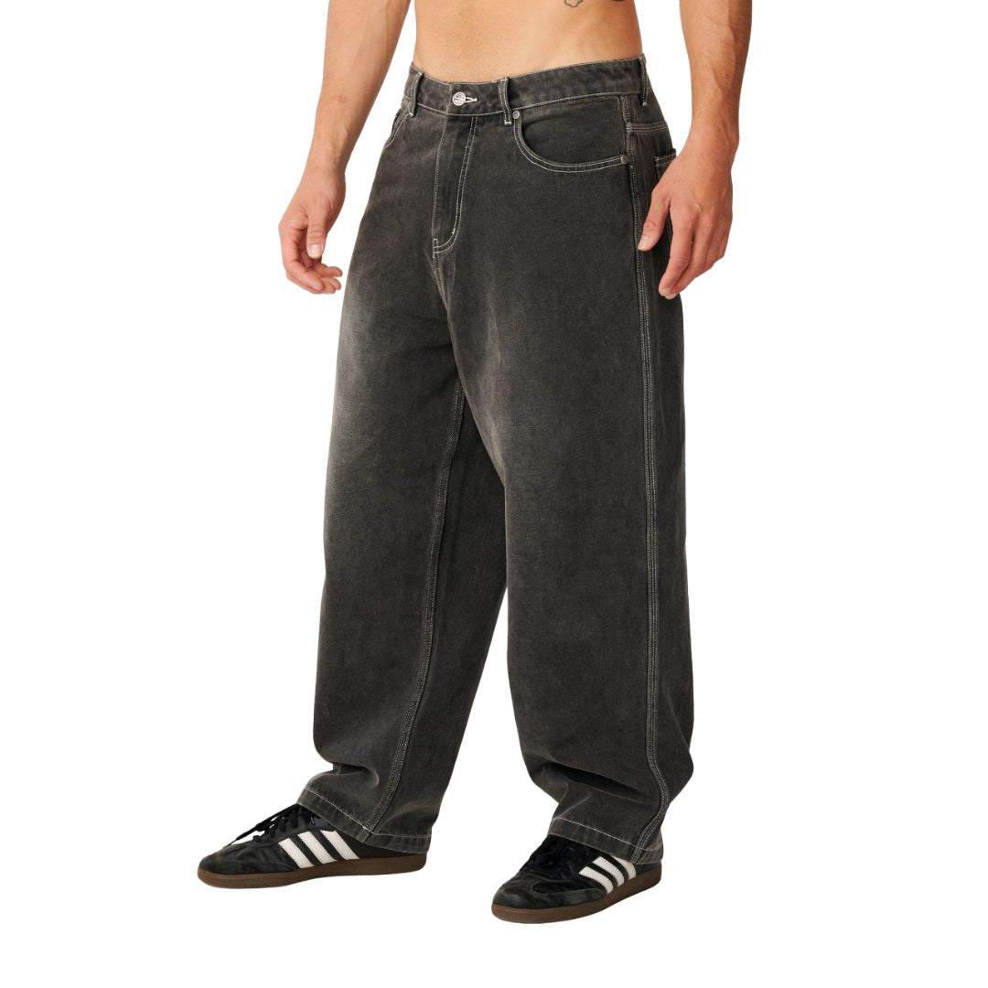 Rip Curl Archive Dirty Denim Pant en Washed Grey, vista lateral de tres cuartos, mostrando la caída suelta del corte baggy y las costuras de contraste.