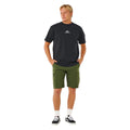 Bermuda híbrida surf Rip Curl Boardwalk Cargo Clásico 20 verde oliva oscuro, vista frontal completa con camiseta negra Rip Curl y zapatillas Vans.