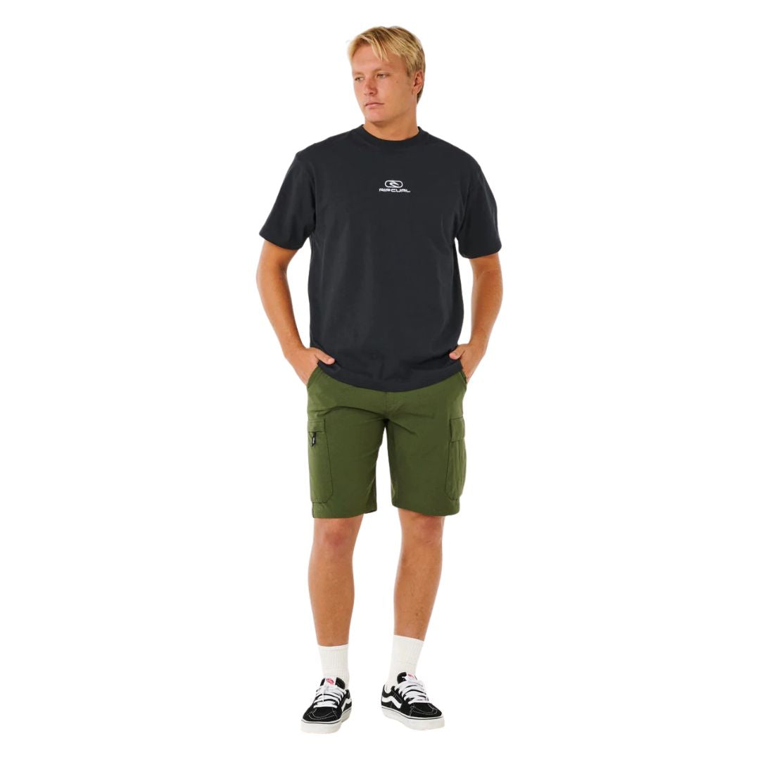 Bermuda híbrida surf Rip Curl Boardwalk Cargo Clásico 20 verde oliva oscuro, vista frontal completa con camiseta negra Rip Curl y zapatillas Vans.