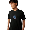 Camiseta Rip Curl Ice Break en negro lavado (Washed Black), vista de detalle del pecho con el logo circular Rip Curl Wet Suits en tonos morado y azul degradado sobre algodón 100%.
