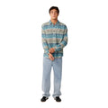 Look completo con camisa Rip Curl Classic Surf Baja Flannel Dusty Jade abierta sobre camiseta, combinada con vaqueros anchos claros. Rayas horizontales en azul, topo y crema de estilo surfero vintage.