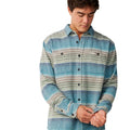 Camisa Rip Curl Classic Surf Baja Flannel en color Dusty Jade, vista frontal con cuello abierto sobre modelo. Rayas jaspeadas en tonos azul verdoso, topo y crema, bolsillo de parche con botón visible.