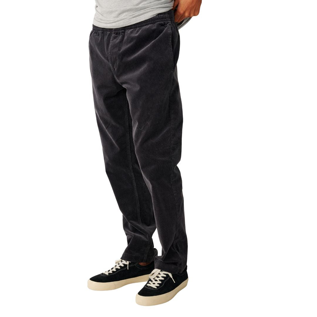Detalle de la pernera y la textura acanalada de la pana del Rip Curl Classic Surf Cord Beach Pant en Washed Black, vista lateral de cuerpo entero.