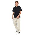 Imagen de modelo masculino con pantalón Rip Curl Classic Surf Double Cord negro, conjunto informal con camiseta clara.