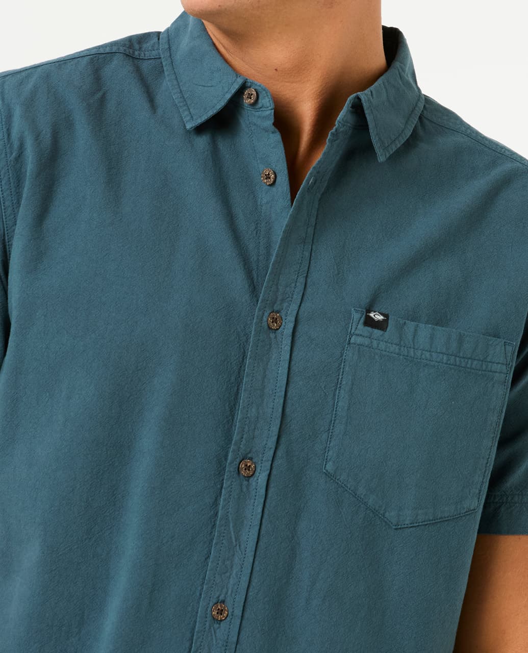 Detalle del bolsillo frontal y botones de la camisa Rip Curl Classic Surf Washed, con etiqueta de la marca.