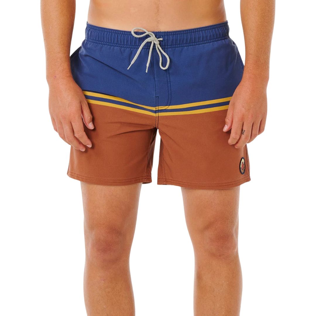 Bañador surf Rip Curl Combine Volley baked clay, vista frontal con color block azul marino y terracota, rayas doradas bordadas en diagonal e insignia Rip Curl.
