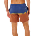 Bañador surf Rip Curl Combine Volley baked clay, vista trasera con color block azul marino y terracota, rayas doradas bordadas y logo sol Rip Curl bordado.