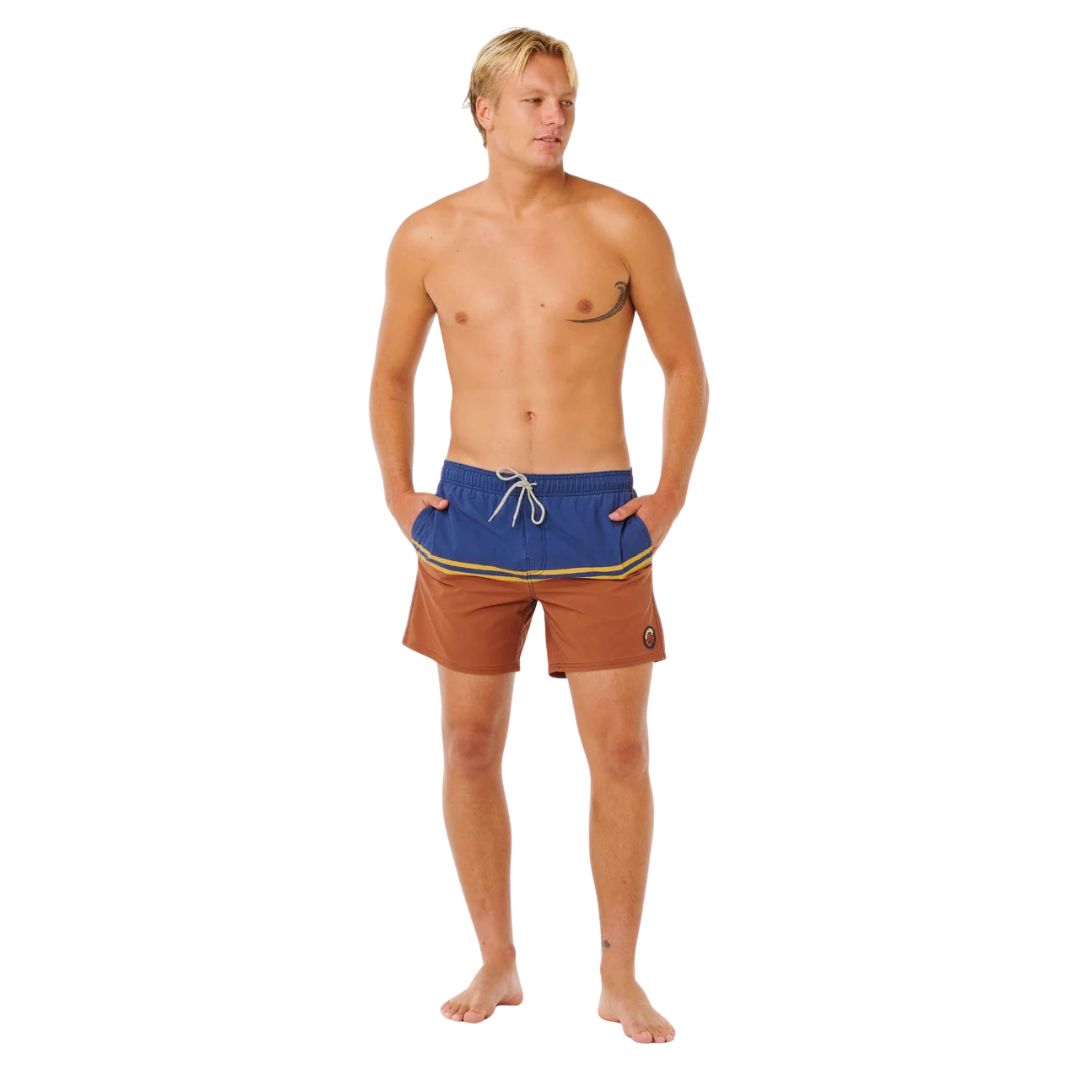 Bañador surf Rip Curl Combine Volley baked clay, vista frontal completa con color block azul marino y terracota, rayas doradas bordadas y volley fit 16 pulgadas.