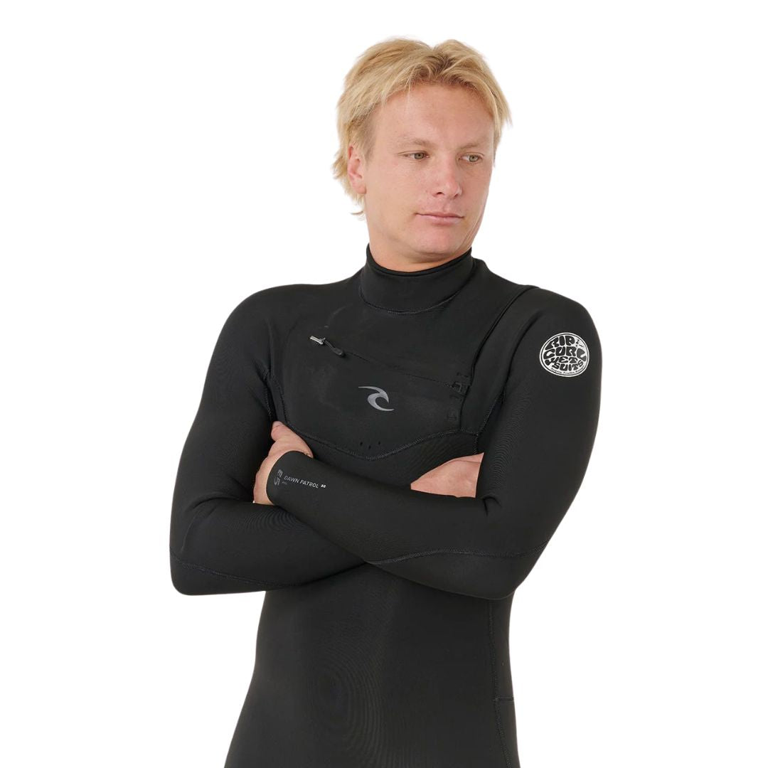 Neopreno surf negro Rip Curl Dawn Patrol Pro Chest Zip 3/2, retrato frontal con brazos cruzados, cremallera pecho y logo Rip Curl Wetsuits en hombro.