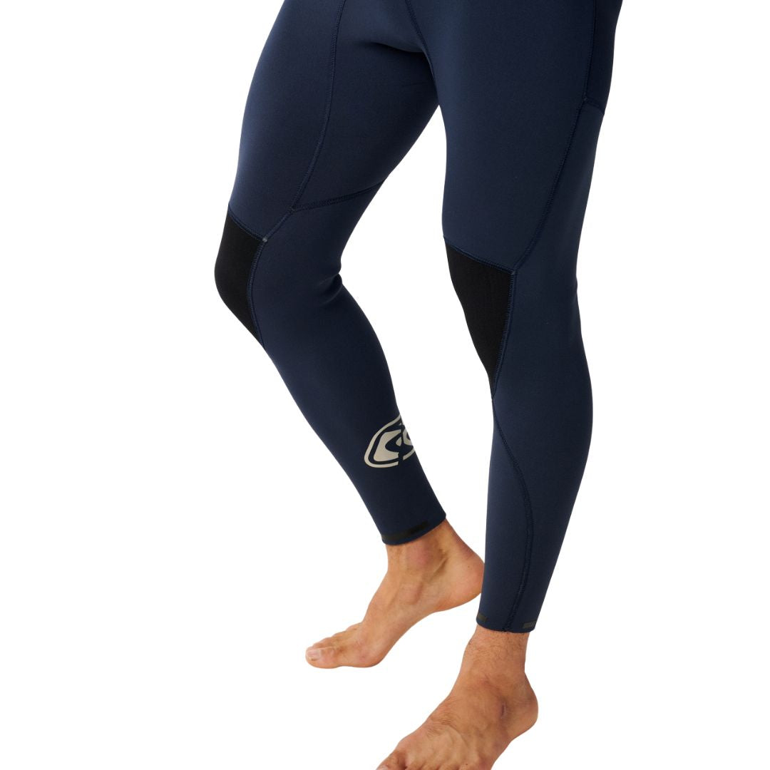 Traje de surf RIP CURL E-BOMB ZIP FREE 4/3 en Navy, primer plano de las piernas mostrando las rodilleras reforzadas en negro y el logotipo en el tobillo, corte ergonómico para libertad de movimiento.