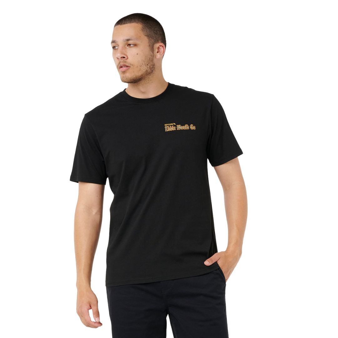 Camiseta Rip Curl EWG Comp Tee color negro, con gráfico Eddie Aikau, vista frontal en modelo.
