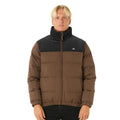 Modelo luciendo la chaqueta Rip Curl Fade Out Cord Puffer marrón y negra, con cremallera hasta el cuello.