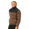 Vista lateral de la chaqueta Rip Curl Fade Out Cord Puffer marrón y negra, con modelo de perfil.