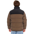 Modelo con chaqueta Rip Curl Fade Out Cord Puffer marrón/negra, vista frontal con manos en bolsillos.