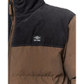 Primer plano del tejido exterior y logotipo bordado de la chaqueta Rip Curl Fade Out Cord Puffer.