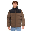 Modelo con chaqueta Rip Curl Fade Out Cord Puffer marrón y negra en pose relajada, vista frontal.