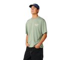 Camiseta Rip Curl Fade Out Icon Tee hombre color sage, corte oversized, logo Rip Curl pequeño en pecho izquierdo, gorra a juego, vista frontal.