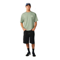 Camiseta Rip Curl Fade Out Icon Tee hombre color sage, cuerpo entero, combinada con bermuda negra y zapatillas, look surfero casual.