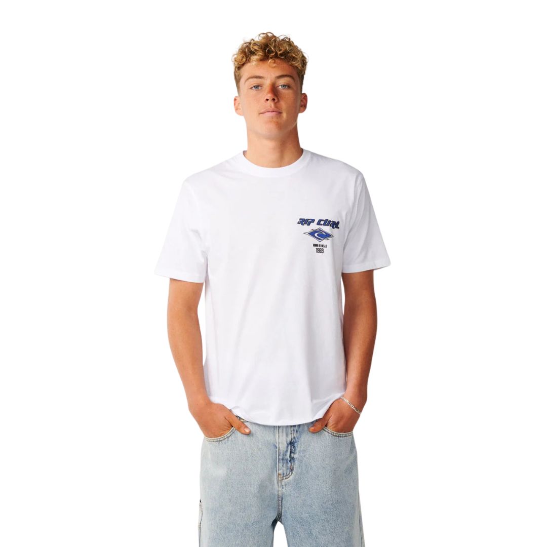 Camiseta Rip Curl Fade Out Icon Tee hombre color blanco, vista frontal, logo Rip Curl azul en pecho, combinada con vaquero ancho.