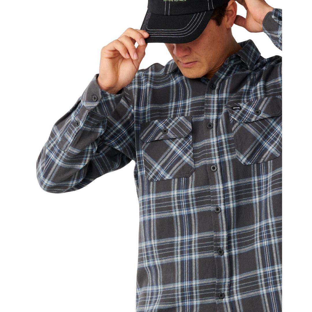 Primer plano del bolsillo de pecho y la botonadura de la Rip Curl Griffin Flannel en Washed Black, mostrando de cerca el estampado de cuadros en azul y gris.