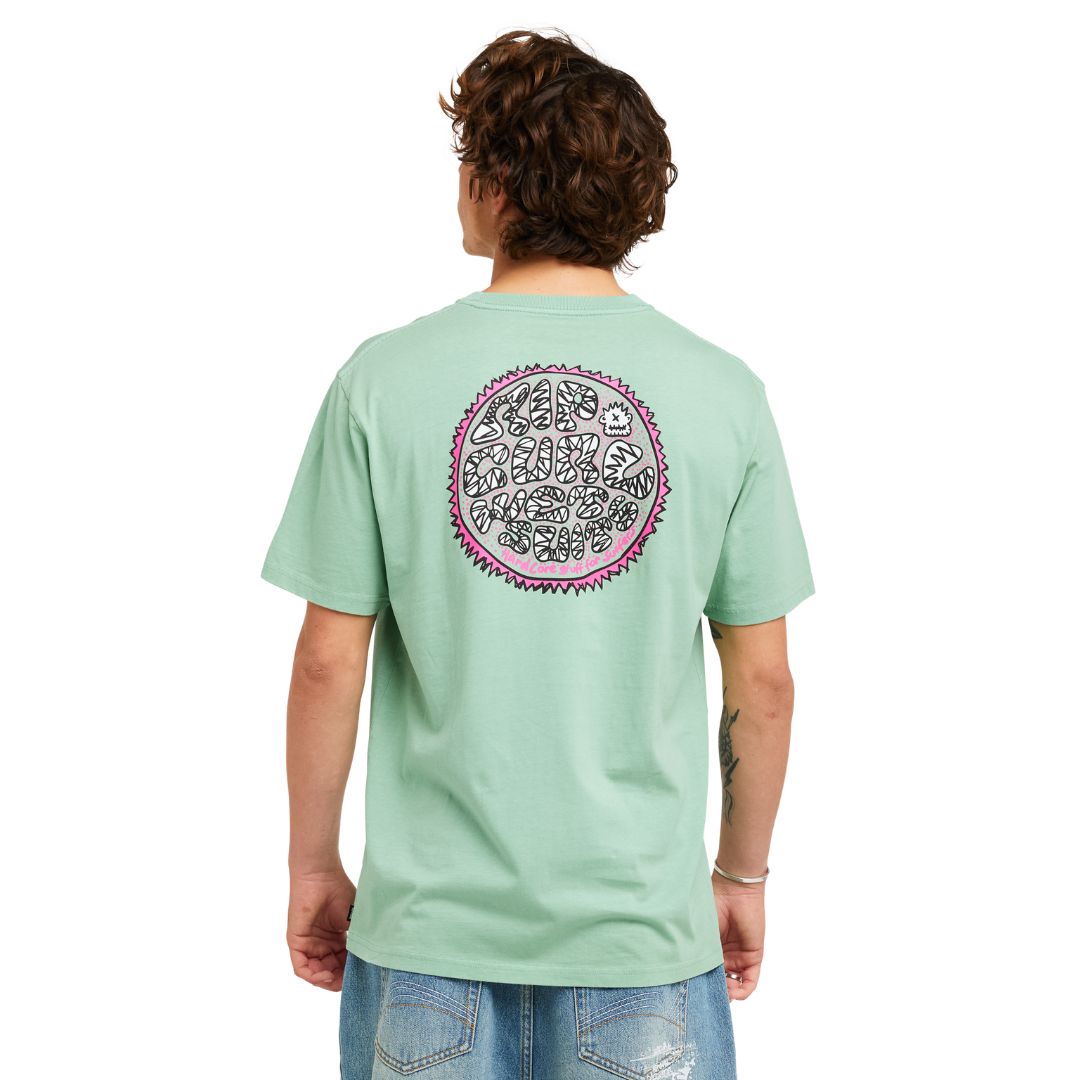 Camiseta RIP CURL HARDCORE TEE SERIES en Aloe, vista trasera completa con estampado circular grande "Rip Curl Wetsuits - Hard Core Stuff For Surfers" en rosa y negro sobre fondo verde menta.
