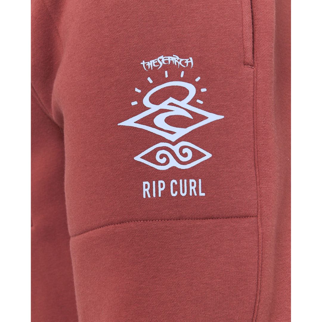 Primer plano del logotipo gráfico en la pierna del pantalón Rip Curl Icons of Surf Apple Butter con diseño blanco serigrafiado.