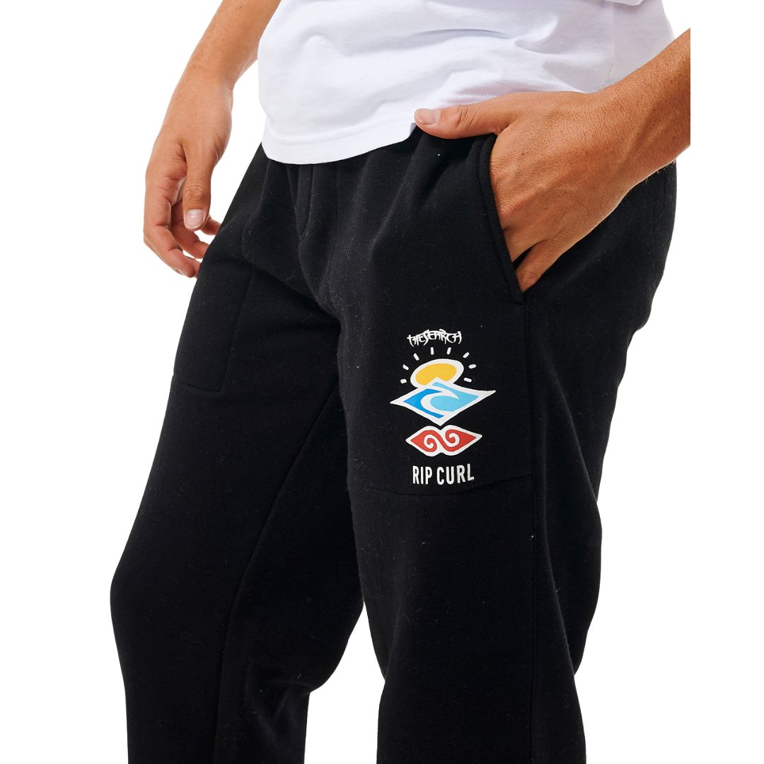 Detalle del pantalón Rip Curl Icons of Surf negro, logotipo gráfico en la pierna y tejido de felpa suave.