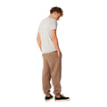 Rip Curl Icons of Surf Trackpant en Walnut combinado con camiseta gris, vista trasera de cuerpo entero mostrando la caída del pantalón.