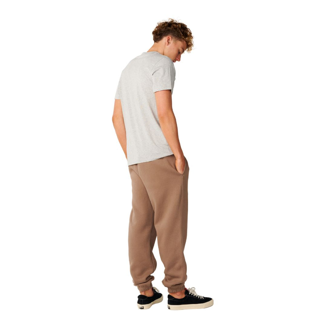 Rip Curl Icons of Surf Trackpant en Walnut combinado con camiseta gris, vista trasera de cuerpo entero mostrando la caída del pantalón.