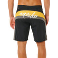 Bañador surf Rip Curl Mirage Archive amarillo y negro, vista trasera con panel cut-and-sew amarillo, logo script Rip Curl blanco y etiqueta Mirage en cinturilla.