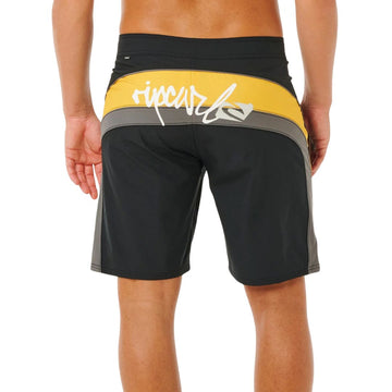 Bañador surf Rip Curl Mirage Archive amarillo y negro, vista trasera con panel cut-and-sew amarillo, logo script Rip Curl blanco y etiqueta Mirage en cinturilla.