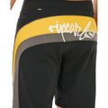 Detalle trasero bañador surf Rip Curl Mirage Archive amarillo y negro, etiqueta Mirage en cinturilla, panel amarillo con logo script y piping gris cut-and-sew.