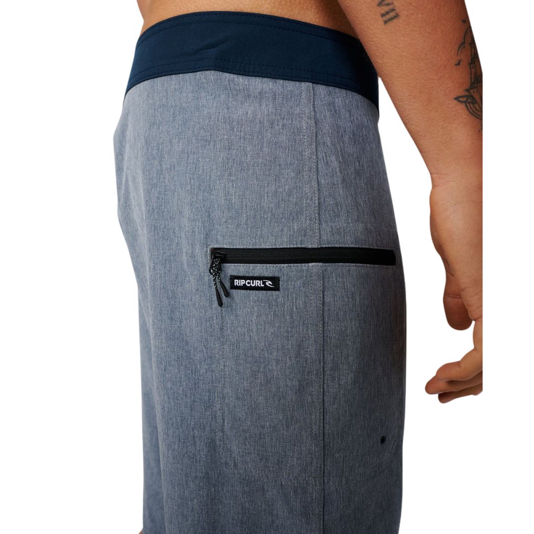 Detalle bolsillo lateral con cremallera negra y etiqueta Rip Curl bordada en boardshort Mirage Core Navy azul marino.