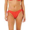 Braguita bikini Rip Curl Oasis Skimpy Pant roja, vista frontal con tejido broderie calado floral y lazos laterales funcionales rojos.