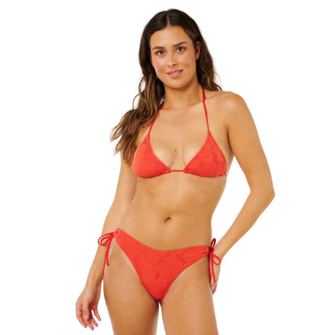 Top bikini triángulo surf Rip Curl Oasis rojo broderie floral, vista lateral con conjunto coordinado y braguita con lazos rojos laterales a juego.