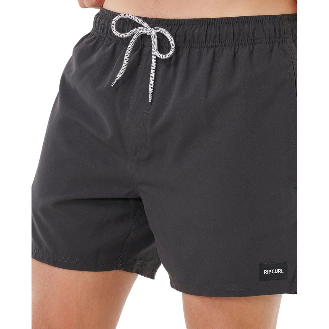 Detalle de bañador surf Rip Curl Offset Daily Volley negro, primer plano de cintura elástica, cordón blanco trenzado y etiqueta tejida Rip Curl.