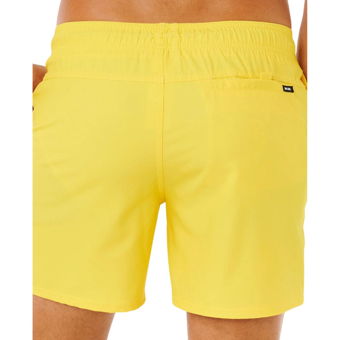 Detalle trasero de bañador surf Rip Curl Offset Daily Volley amarillo brillante, bolsillo con velcro, etiqueta Rip Curl y cintura elástica.