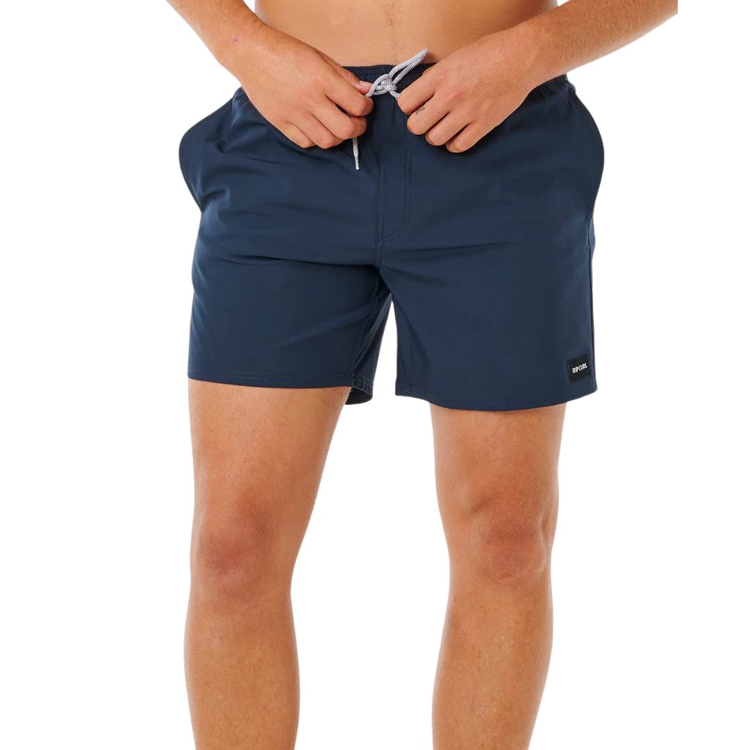 Hombre ajustando el cordón del bañador Rip Curl Offset Daily Volley 16" azul marino con etiqueta tejida Rip Curl y corte volley fit de 16 pulgadas.