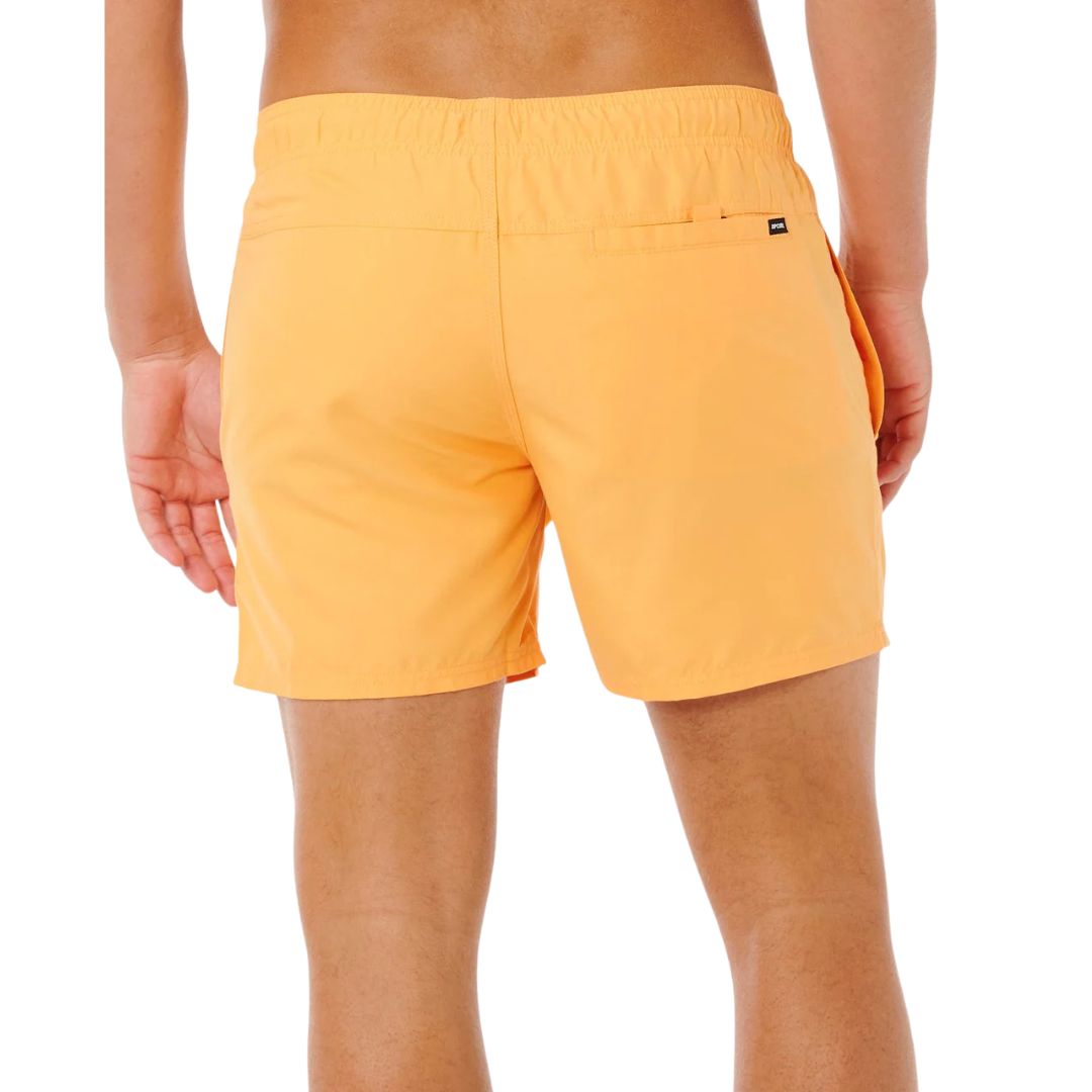Bañador naranja vivo Rip Curl Offset Volley, vista lateral con mano en bolsillo, cinturilla elástica con cordón gris y etiqueta Rip Curl en bajo.