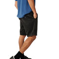 Pantalón corto pana Rip Curl Premium Surf Cord negro, vista lateral con camiseta azul, mano en bolsillo y logo bordado circular en pana acanalada acid wash.