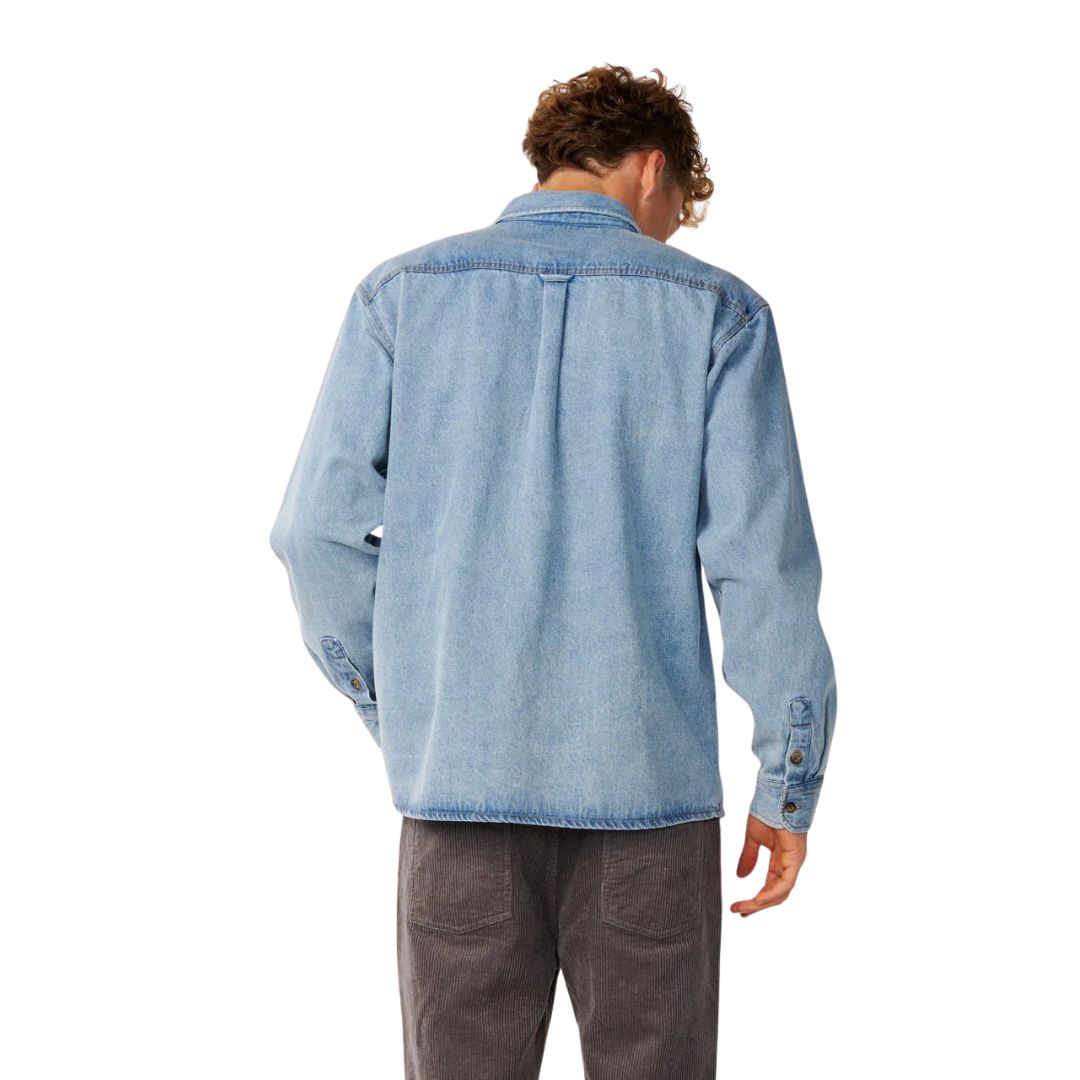 Vista trasera de la camisa vaquera Rip Curl Premium Surf Denim L/S en Washed Blue, con canesú trasero, corte holgado y puño de botón visible en la manga larga.