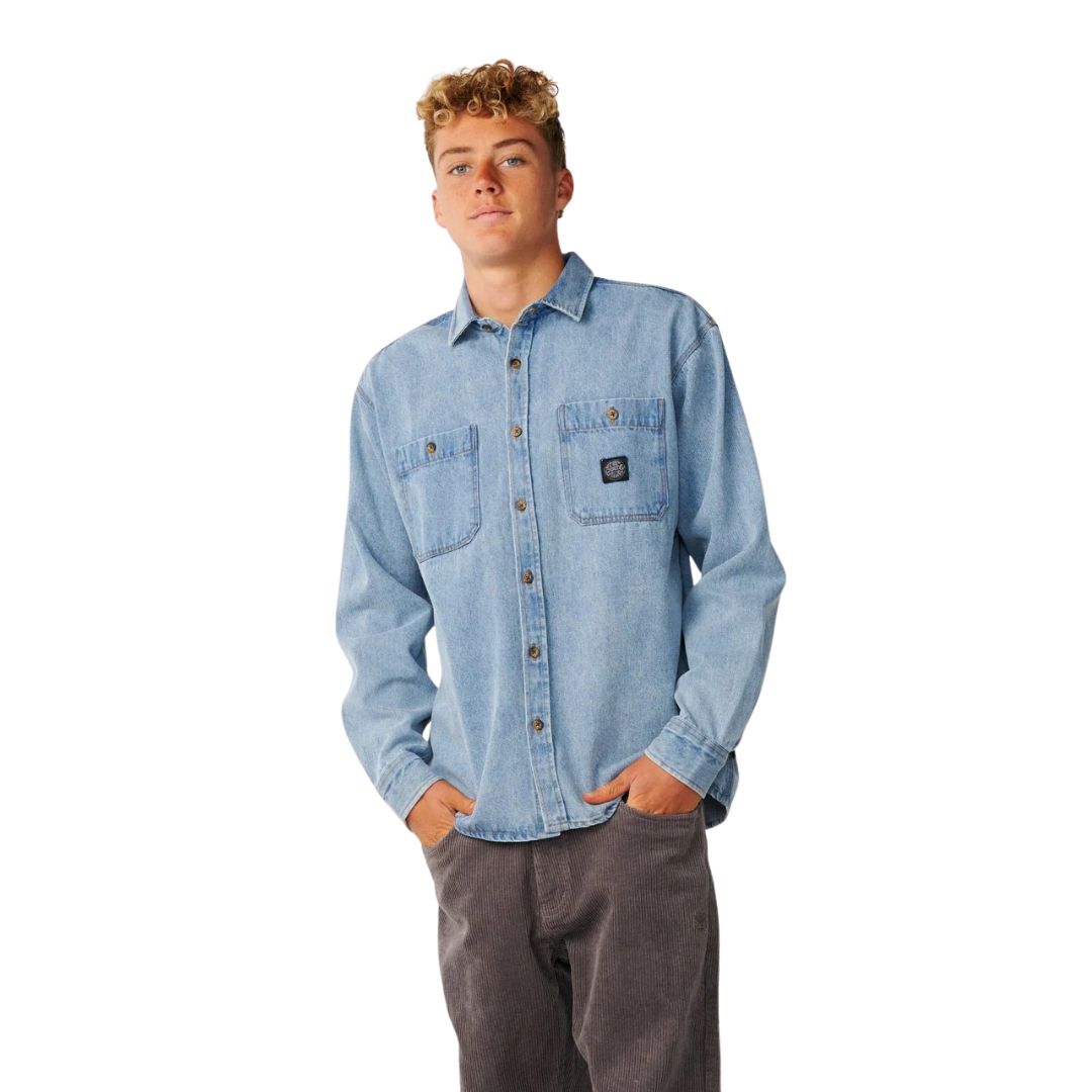 Vista frontal de la camisa vaquera Rip Curl Premium Surf Denim L/S en Washed Blue, con dos bolsillos de parche en el pecho, parche tejido Rip Curl y cierre de botones completo.